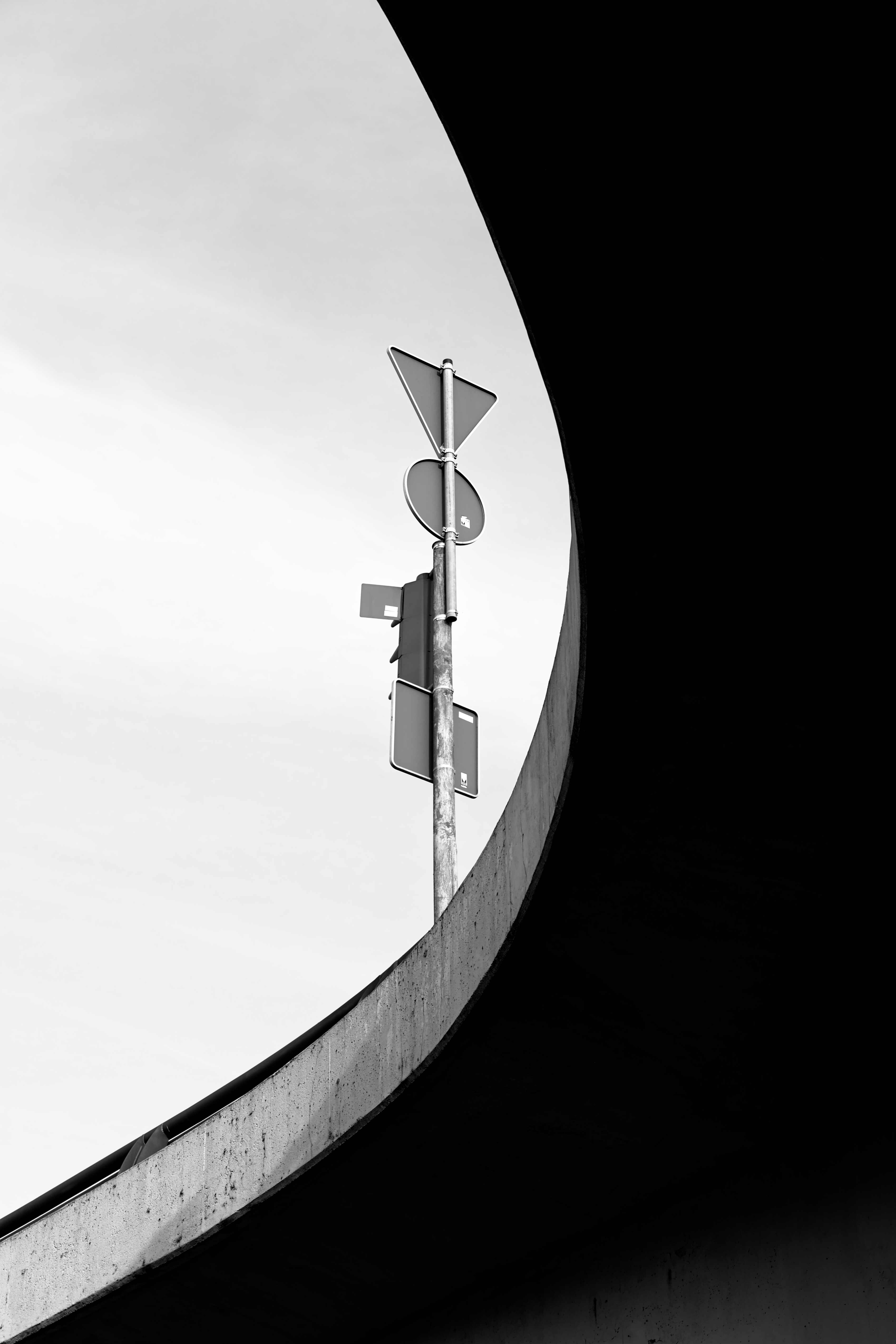 view up a concrete bridge from below. A street sign points into the sky.